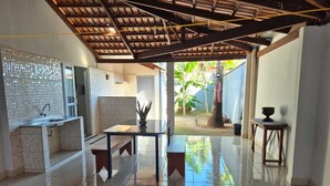A modern kitchen with a tiled backsplash, a built-in sink, and a dining area with a glass table and benches. - Vacation Home - Recanto Flor de Laranjeira, Palmas-Tocantins. (Palmas)