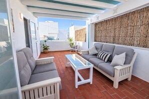 Un patio con dos sofás grises, una mesa de centro blanca y una pared de bambú.