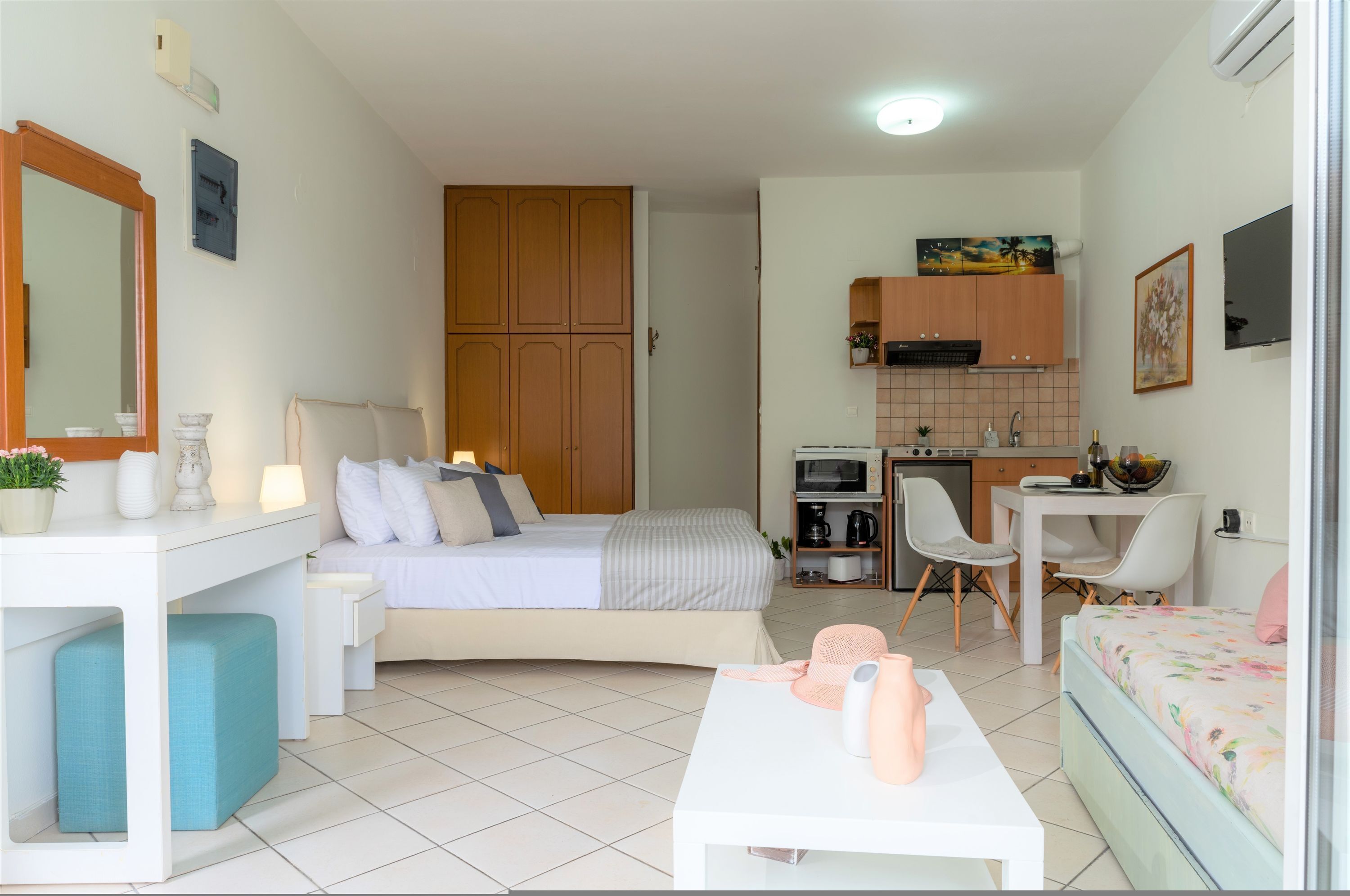 A compact room with a bed, a desk, a kitchenette, and a small seating area.