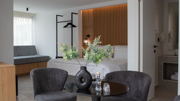 Moderni hotellihuone, jossa on sänky, oleskelualue, ruokapöytä ja kylpyhuone.