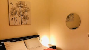 Ett hotellrum med en säng, en tavla, en rund spegel och en lampa.