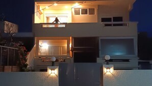 Ein modernes, zweistöckiges Haus mit Balkon, Garage und Auffahrt.