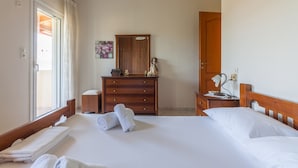 Ein Hotelzimmer mit einem Bett, einem Holzschrank, einem Nachttisch, einem Spiegel und einer Tür.