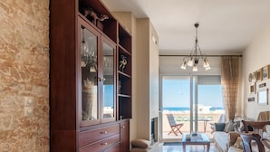 Ein Wohnzimmer mit Holzschrank, einer Kristallleuchter, einem Balkon mit Aussicht und einem Sofa.