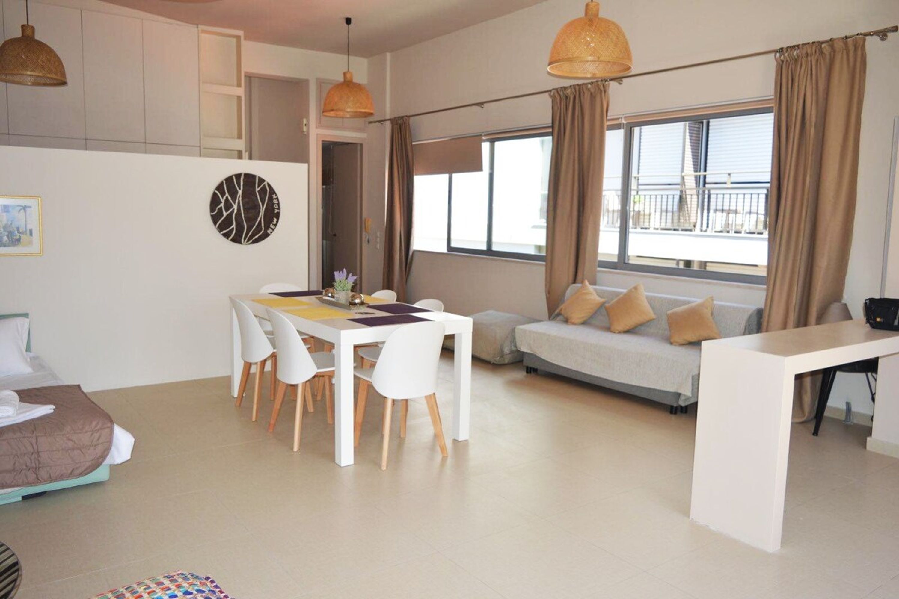 A modern living room with a dining area, a sofa, and a view of the balcony.
