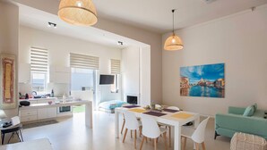 A modern living room with a dining area, a kitchen, and a TV. - The Fifty Condo in Heraklion City Center (Heraklion)