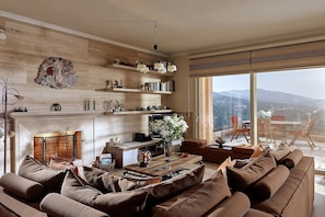 Ein modernes Wohnzimmer mit Kamin, einer Couch, einem Couchtisch und Blick auf die Stadt.