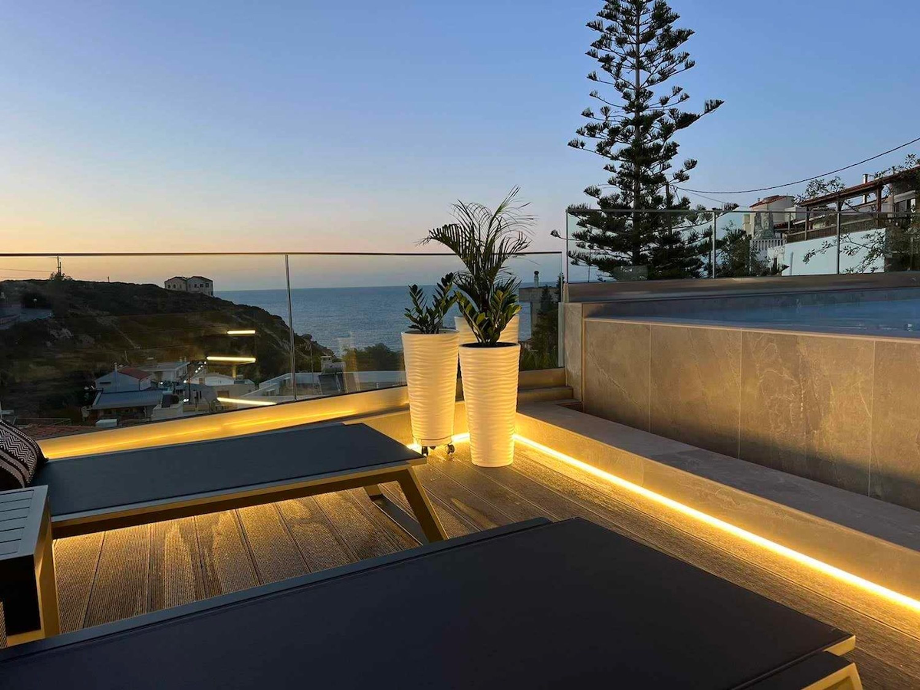 Eine Dachterrasse mit Meerblick, zwei Kübelpflanzen und ein Holzdeck.