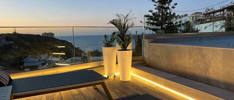 Eine Dachterrasse mit Meerblick, zwei Kübelpflanzen und ein Holzdeck.