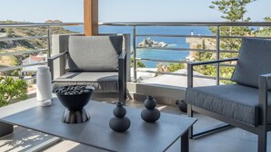 Een balkon met twee grijze banken, een tafel met decoratieve vazen en uitzicht op zee.