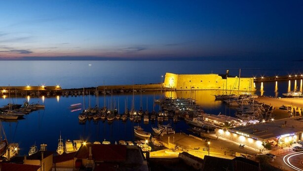 A harbor at dusk with boats docked, a fortified building, and a marina with lights. - Havana 2 Sea and Pool Apartment (Malevizi)