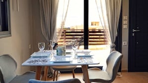 A dining table set with plates, glasses, and cutlery, with a view of a building through sheer curtains. - Havana 2 Sea and Pool Apartment (Malevizi)