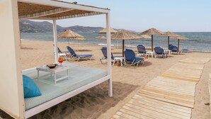 A beachside hotel with a covered seating area, lounge chairs, and umbrellas. - Havana 2 Sea and Pool Apartment (Malevizi)