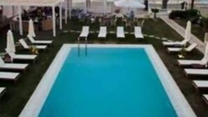 A pool area with lounge chairs and umbrellas, a clear view of the ocean, and a structure with a white roof. - Havana 2 Sea and Pool Apartment (Malevizi)