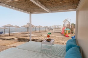 Une chambre donnant sur la plage, avec vue sur la mer, un espace de jeux et une table avec une boisson.