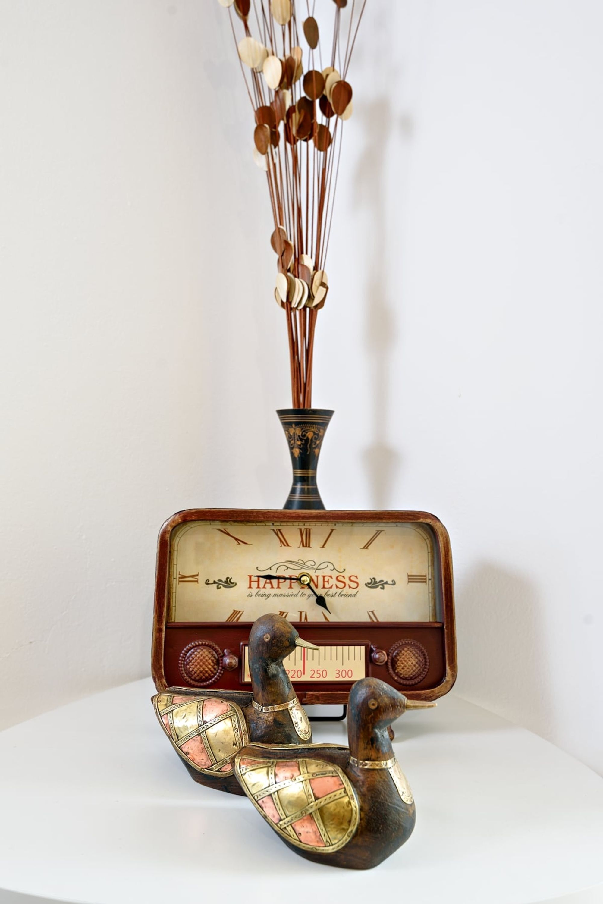 Una radio antigua con un jarrón decorativo y figurillas.
