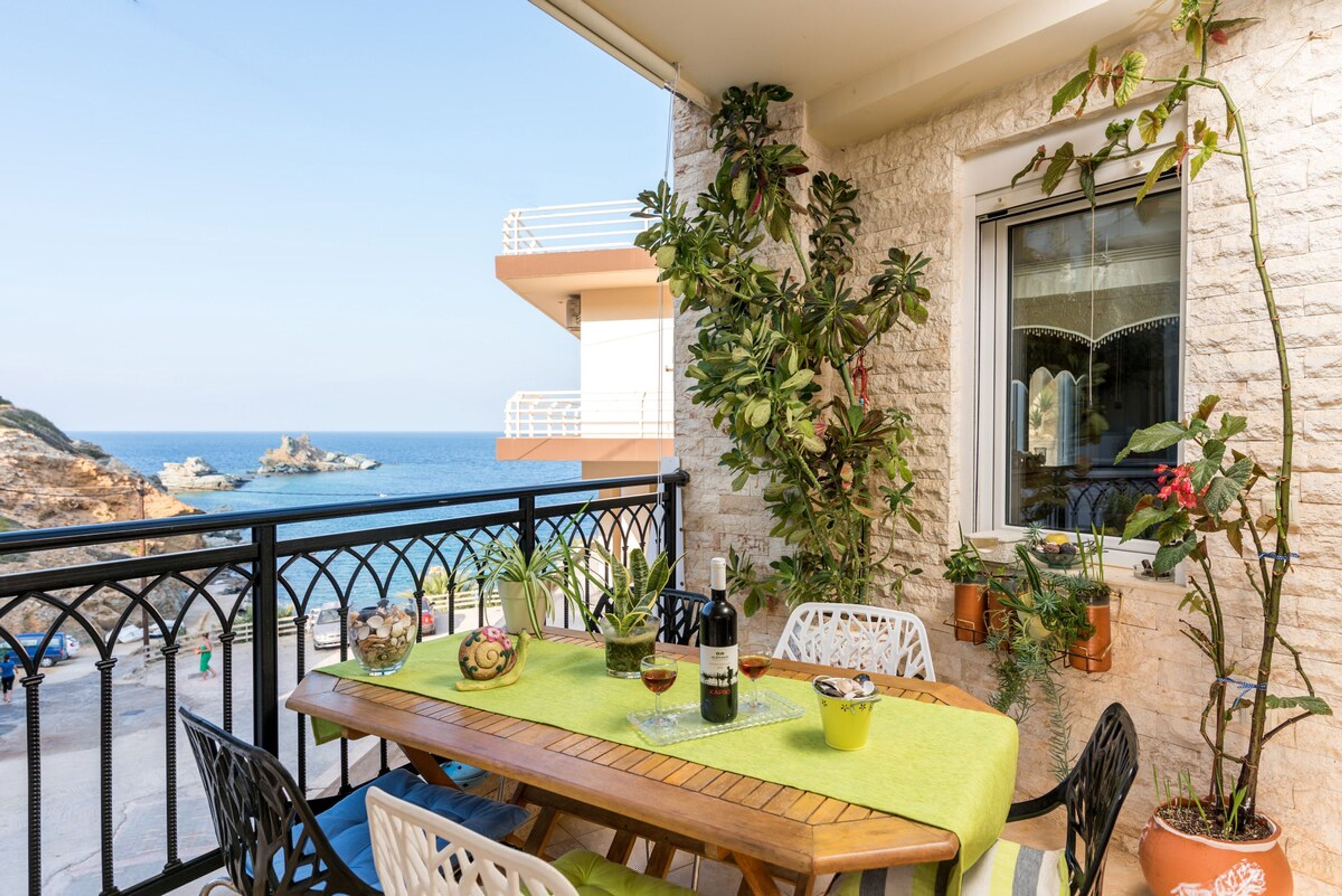 A balcony with a table set for two, overlooking a coastal view.