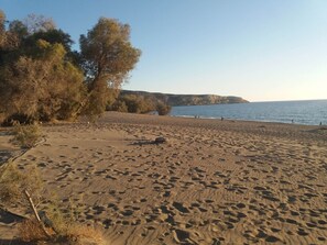 A sandy beach with footprints, trees, and a calm sea. - Marina s Traditional House at Sivas Village (Faistos)