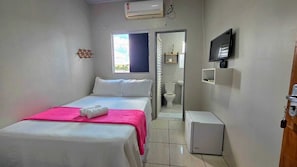A small, clean room with a bed, a TV, a toilet, and a window. - Aurora nascer do sol (Aurora do Tocantins)