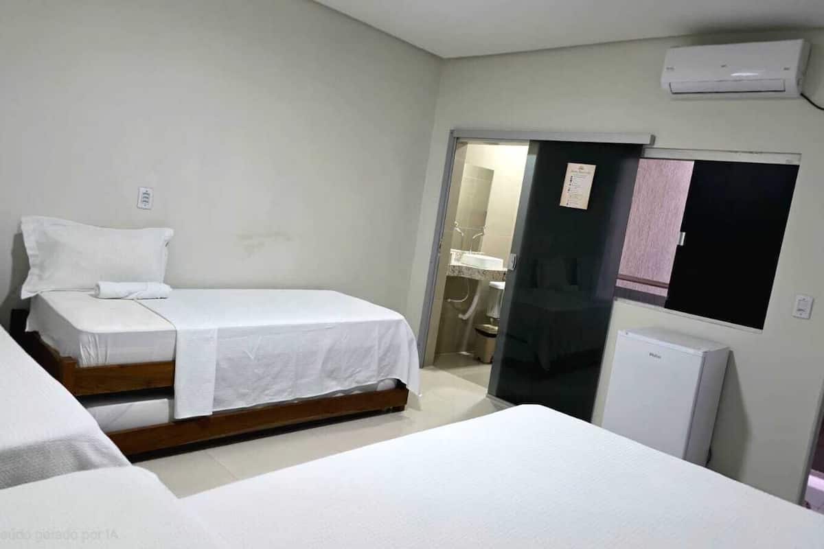 A room with two beds, a small refrigerator, and a mirror on the wall.