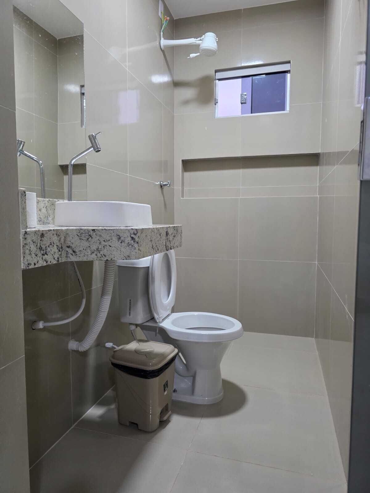 Een badkamer met een wastafel, toilet, douche en een klein raam.