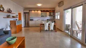 A modern kitchen with a dining area, a large window, and a sliding glass door leading to an outdoor area. - Eleni Sea Luxury Apartment (Malevizi)