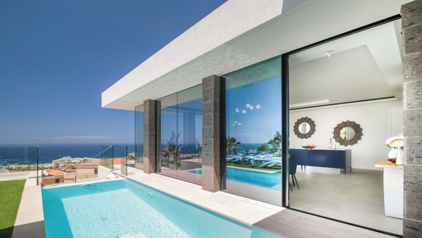 A modern pool area with clear glass walls, a pool, and a view of the ocean. - LUX NEW Villa C with priv heated pool, ocean view (Costa Adeje)