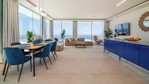 A modern living room with a dining area, a sofa, a TV, and a view of the ocean. - LUX NEW Villa C with priv heated pool, ocean view (Costa Adeje)