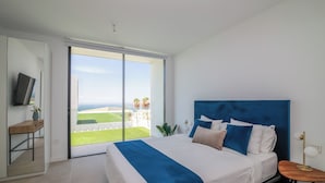 A bedroom with a bed, a TV, a desk, and a view of the outdoors. - LUX NEW Villa C with priv heated pool, ocean view (Costa Adeje)