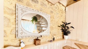 A rustic interior with a stone wall, a wooden staircase, a white-framed mirror, a wooden chest, and a potted plant. - Cozy cottage in the grounds of an old mill (Payrignac)