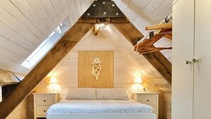A bedroom with a sloped ceiling, a bed, bedside tables, and a wardrobe. - Cozy cottage in the grounds of an old mill (Payrignac)