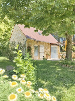 Ein Haus aus Stein mit rotem Dach, einer Haustür und einer kleinen Veranda.