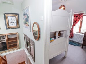 A room with a bunk bed, framed artwork, a mirror, and a window with curtains. - Pencestyll (Cardigan)