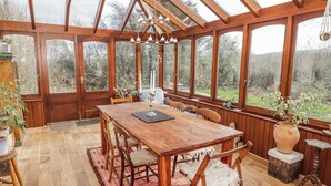 A conservatory with a wooden table, chairs, and a chandelier. - Pencestyll (Cardigan)