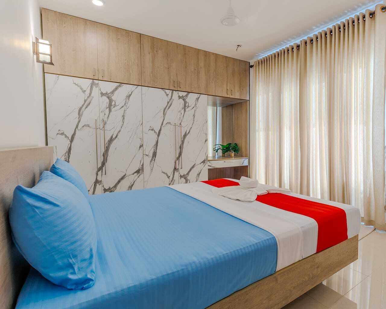 A modern bedroom with a bed, a nightstand, a mirror, and a window with curtains.