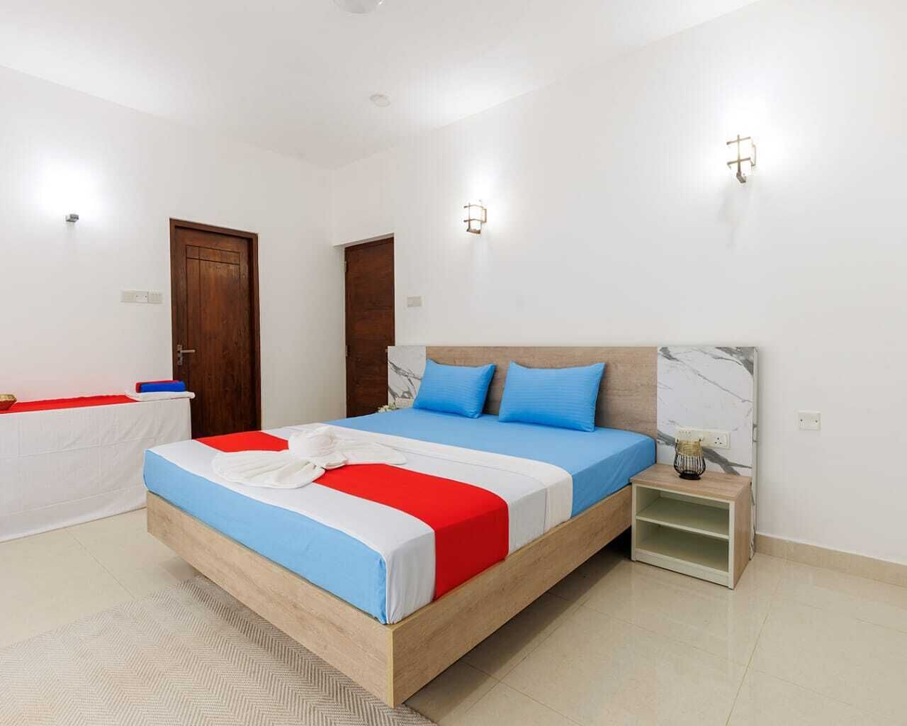 Een slaapkamer met een houten bed, een nachtkastje, een deken met rode en witte strepen, en een hoofdbord met een marmerpatroon.