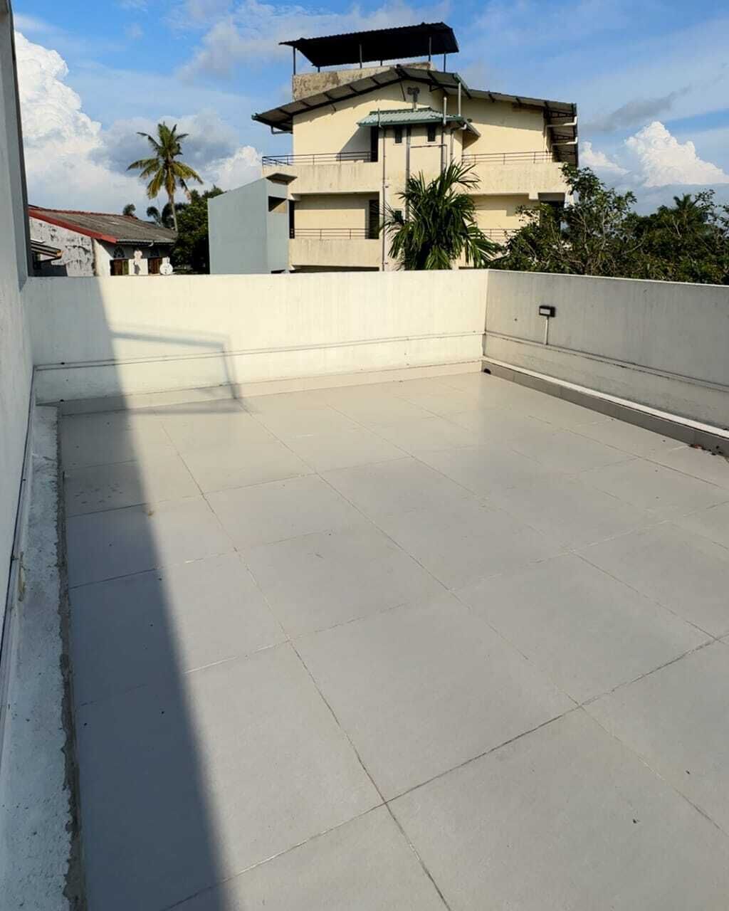 Een terras op het dak met een vlak oppervlak, een gebouw op de achtergrond en een heldere lucht.