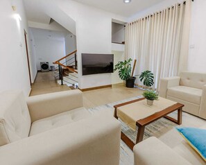 A living room with a sofa, a coffee table, a TV, and a staircase leading to an upper floor. - 4BR Family Friendly Oasis in Pannipitiya, Colombo (Pannipitiya)