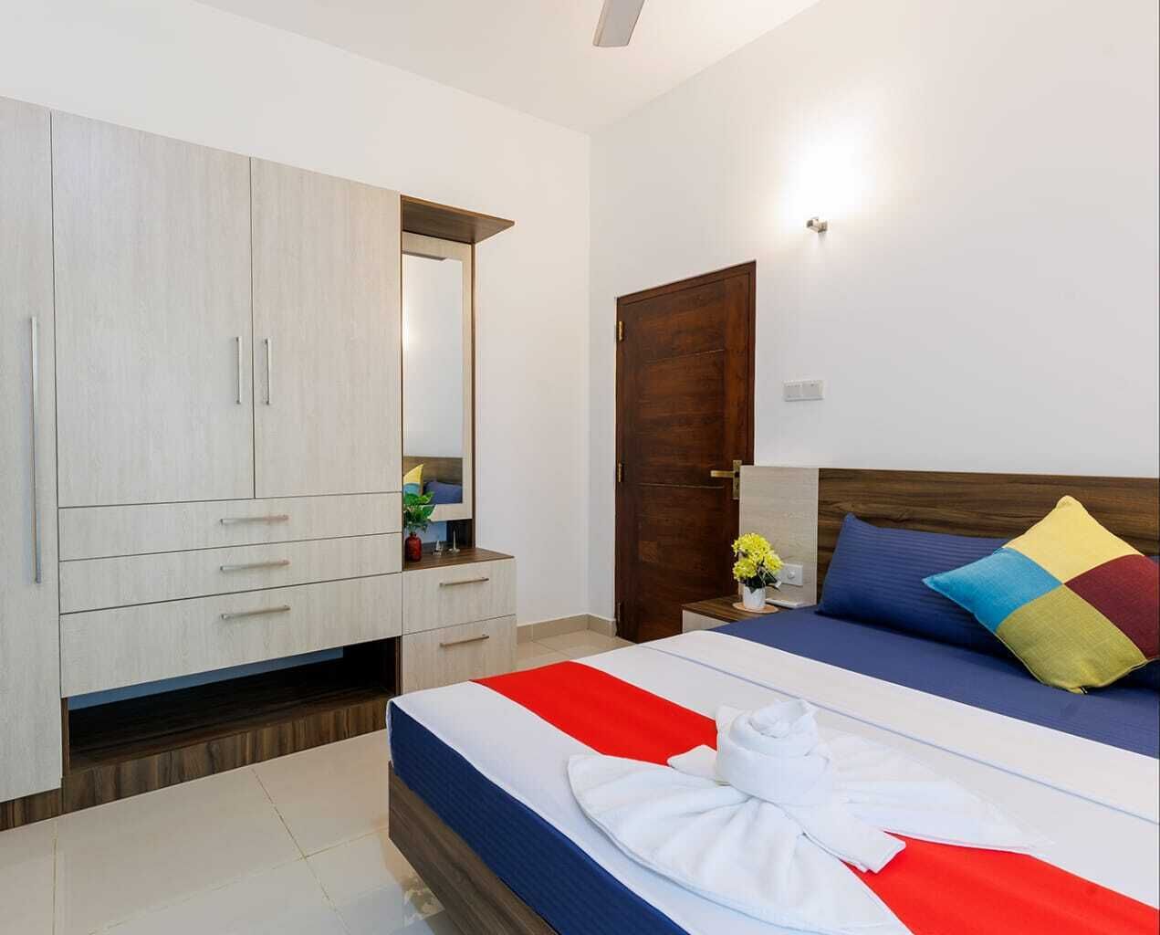 Ein Schlafzimmer mit Bett, Kleiderschrank, Nachttisch und einer Tür.