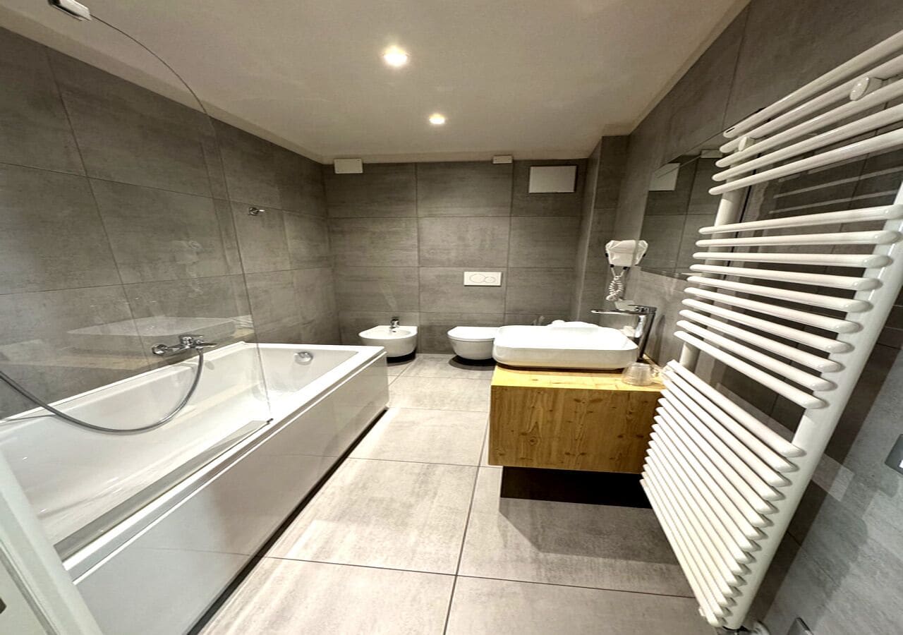Un baño moderno con bañera, inodoro, lavamanos y un perchero para toallas.