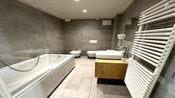 Un baño moderno con bañera, inodoro, lavamanos y un perchero para toallas.