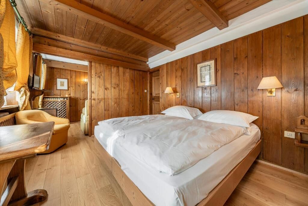 A wooden room with a bed, a chair, and a table.