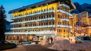 A multi-story hotel with balconies, a snow-covered ground, and a mountainous backdrop. - Parc Hotel Victoria (Cortina d'Ampezzo)
