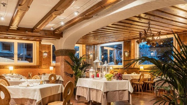 A restaurant with wooden beams, tables set for dining, and large windows. - Parc Hotel Victoria (Cortina d'Ampezzo)