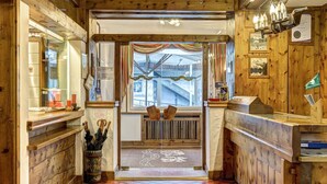 A wooden interior with a patterned floor, a bench, and a window with curtains. - Parc Hotel Victoria (Cortina d'Ampezzo)