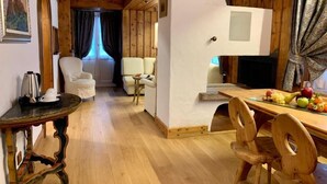 A wooden interior with a dining table, chairs, a sofa, and a television. - Parc Hotel Victoria (Cortina d'Ampezzo)