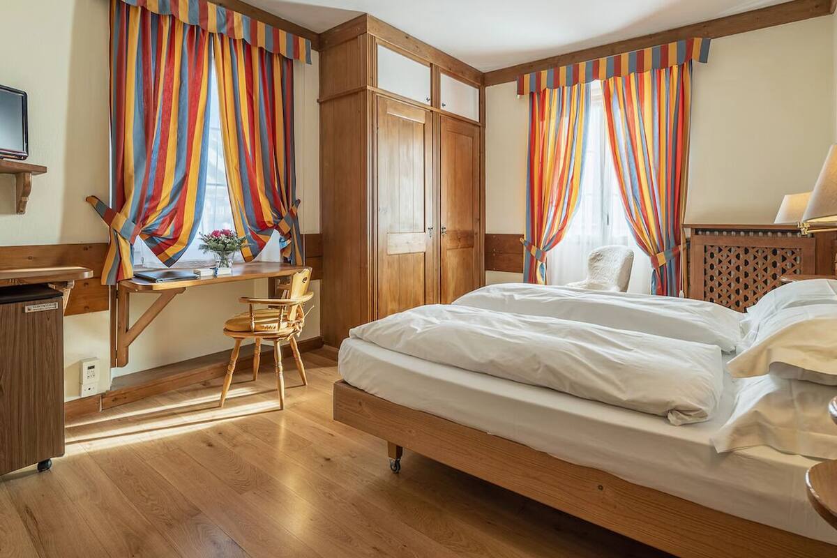 A bedroom with a wooden bed, a desk with a chair, and a wardrobe.
