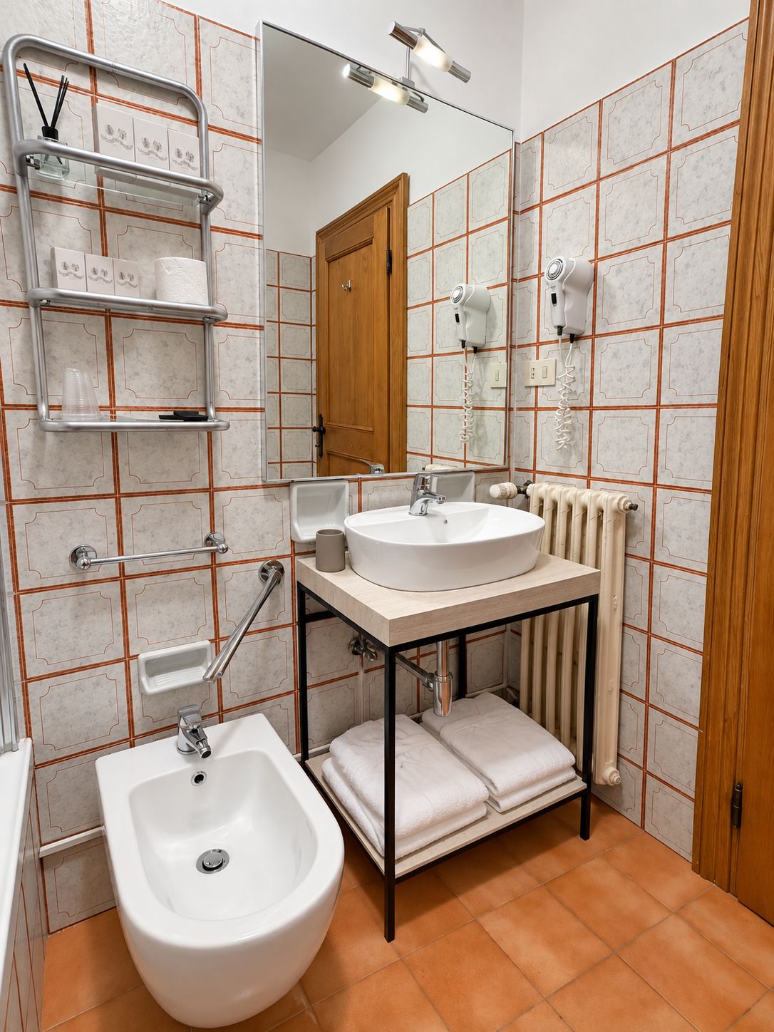 A bathroom with a bidet, a sink, a mirror, and a towel rack.