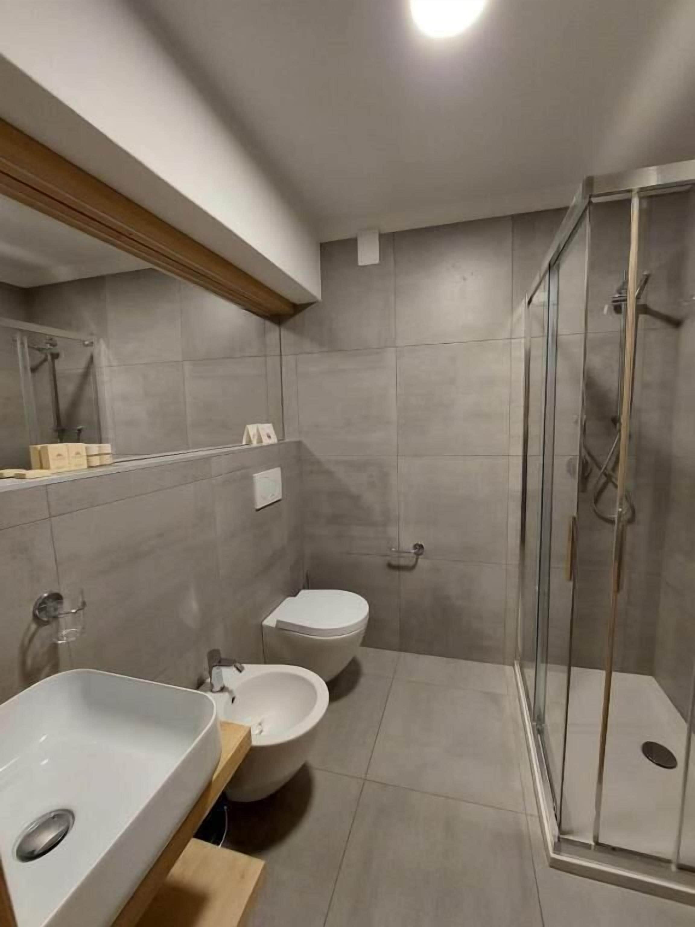A modern bathroom with a shower, toilet, and sink.