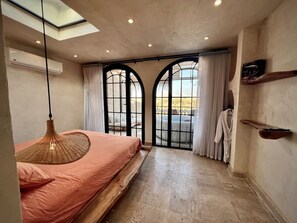 A bedroom with a bed, a hanging light fixture, a window with curtains, and a view of the outside. - Suspiroo w/skylight and private terrace (Cairo)